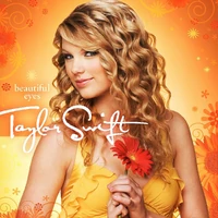 A female with curly blond hair looks forward in a semi-right profile pose. She holds a flower against her chest, which is clothed by a yellow blouse. The background alternates between different yellow and orange values while hosting floral patterns.