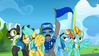 A pony holds up the blue team flag S3E07