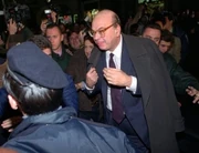 Bettino Craxi, viewed by many as the symbol of Tangentopoli, leader of the Italian Socialist Party, is greeted by a salvo of coins as a sign of loathing by protesters.